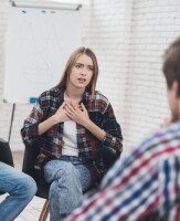 Junge Frau spricht offen in einer Gruppentherapie oder Gesprächsrunde